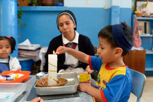Schwester Guadalupe unterstützt Paulo, 3 Jahre, beim Anzünden einer Kerze, Montessori-Kindergarten und -Grundschule "Kinderhaus Santa Maria Magdalena Postel", Cochabamba, Departamento Cochabamba, Bolivien. (Foto: Florian Kopp)