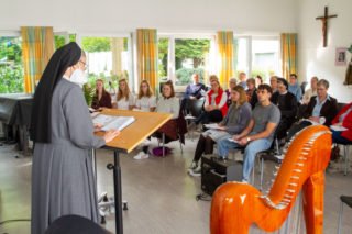 Schwester Laetitia Müller eröffnet die Aussendungsfeier in der Musikaula des Berufskollegs Bergkloster Bestwig. Foto: SMMP/Ulrich Bock